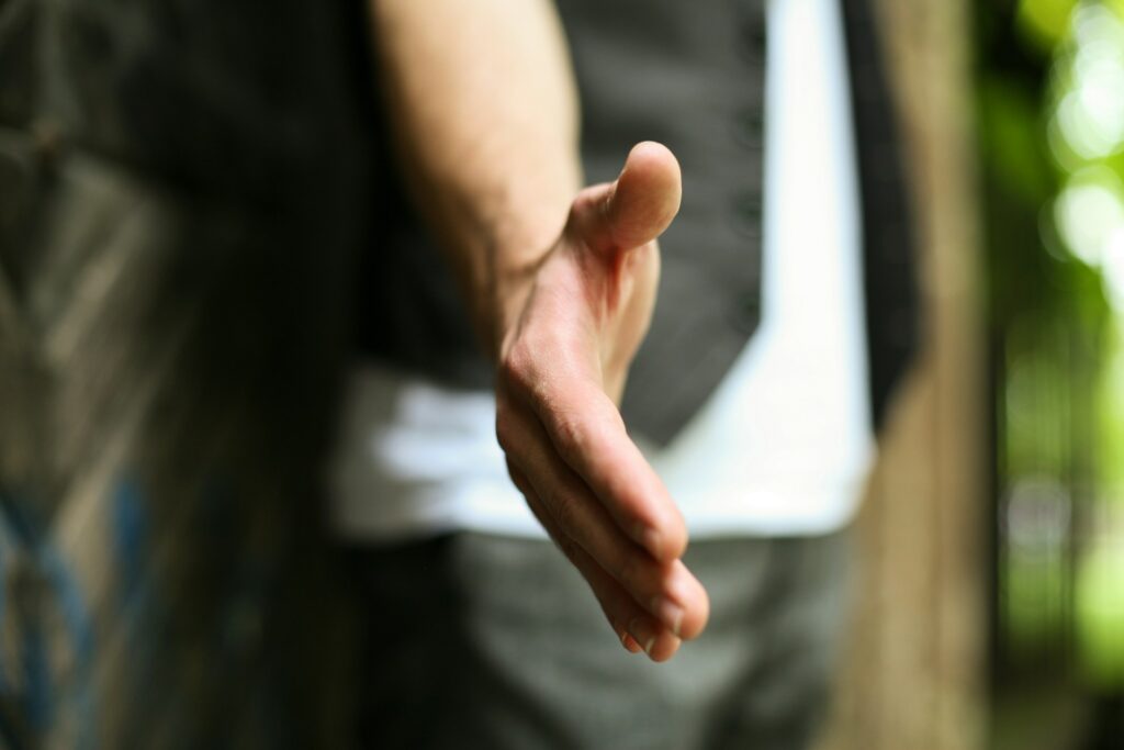 Person extending hand for support in mental health recovery.