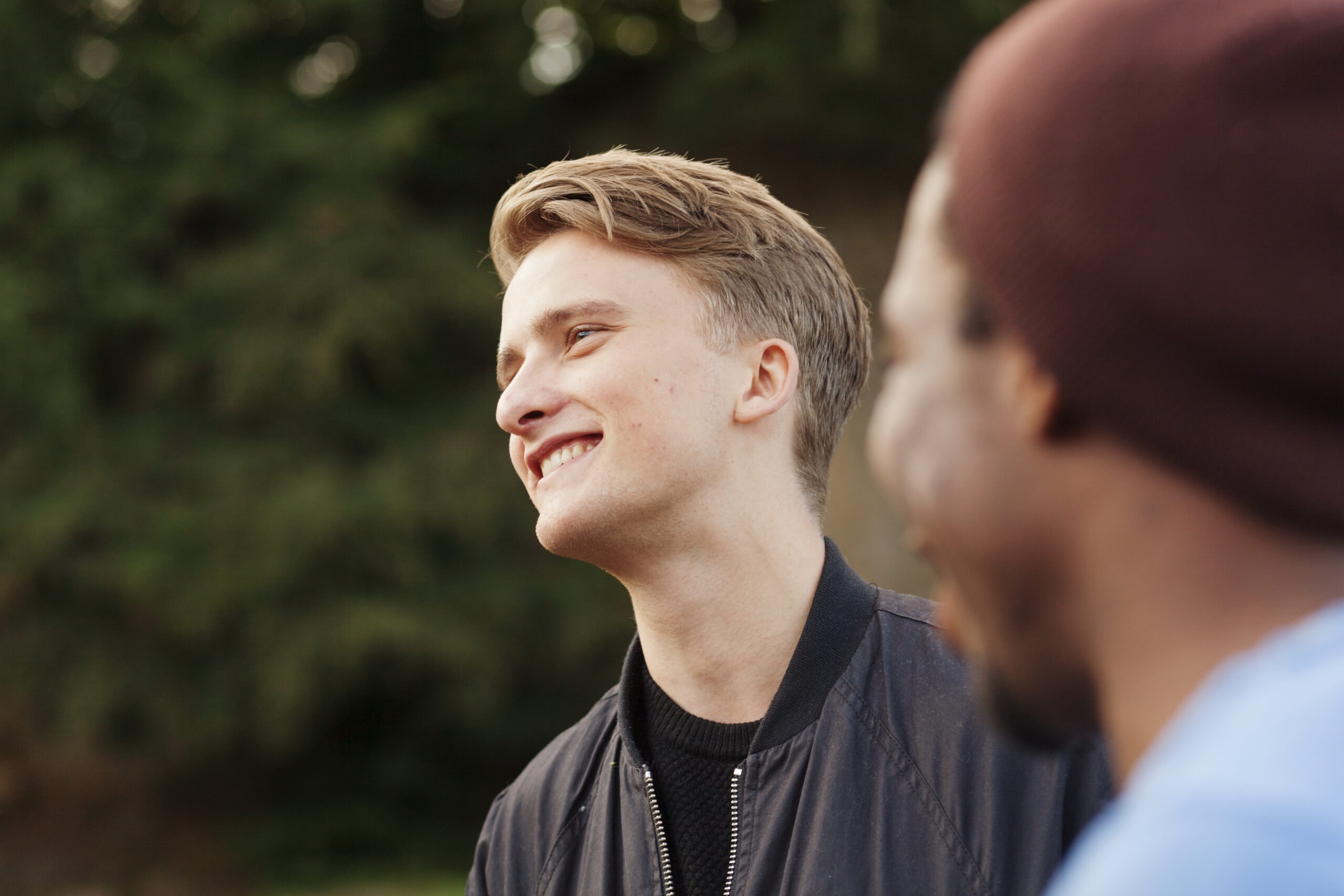 Young man smiling outdoors, receiving compassionate mental health care.