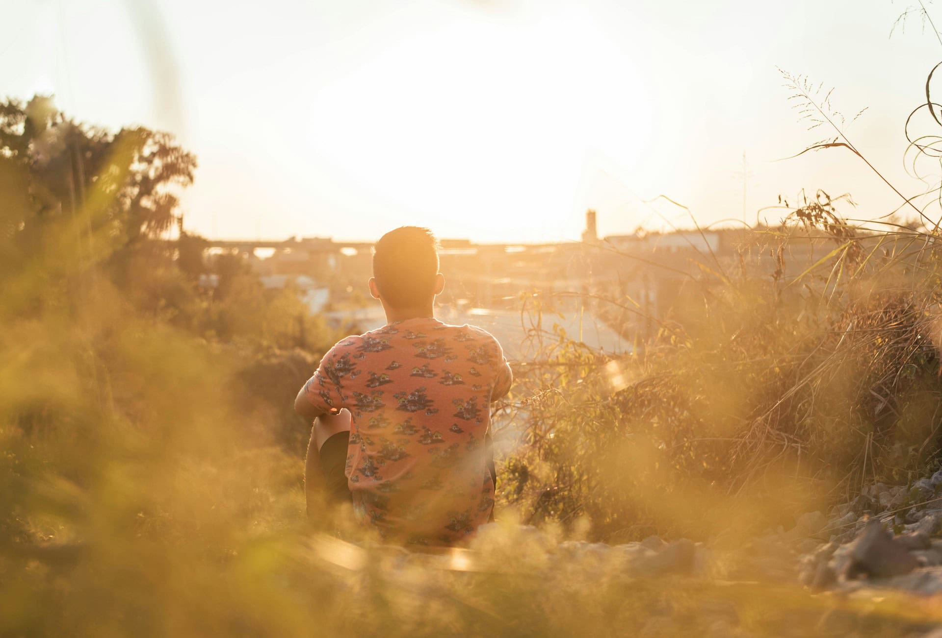 Person sitting outdoors during sunset promoting mental health and well-being.