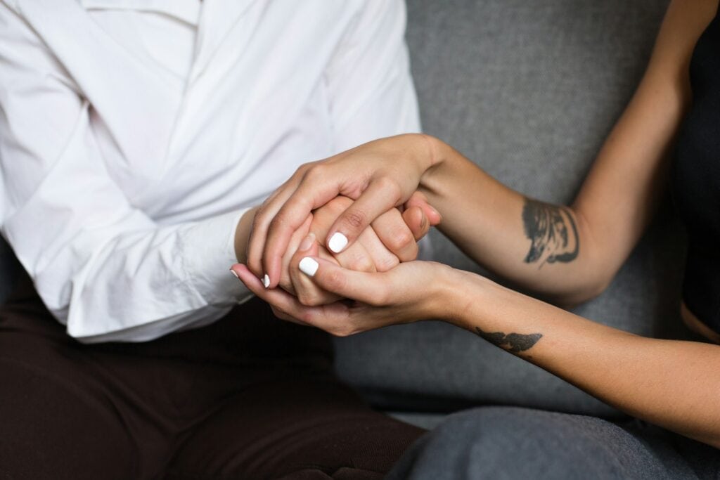 Two individuals holding hands, symbolizing support and care in mental health treatment.
